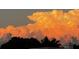 Expansive sky filled with beautiful billowing, light orange clouds over a dark treeline at 7233 15Th Ne Ct, St Petersburg, FL 33702