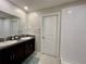 This bathroom features dual sinks, a large mirror, and a tiled shower for a clean and luxurious feel at 13621 Willow Bluestar Loop, Riverview, FL 33579