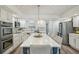 Modern kitchen boasts white cabinets, stainless steel appliances, and a large center island with pendant lighting at 13945 75Th Ave, Seminole, FL 33776