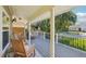Inviting covered patio with wooden chairs, a swing, and serene views of the manicured garden and street at 13945 75Th Ave, Seminole, FL 33776
