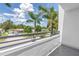 Balcony view showcasing lush palms, blue sky, and residential street at 2246 Fiesta Dr, Sarasota, FL 34231