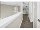 Hallway with gray wood-look floors, neutral walls, and white trim leads to bedrooms and bathrooms at 2246 Fiesta Dr, Sarasota, FL 34231