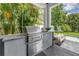 Outdoor kitchen featuring stainless steel grill and lush, tropical landscaping at 2246 Fiesta Dr, Sarasota, FL 34231