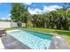 A stunning pool with clear blue water surrounded by lush green grass and privacy landscaping at 2246 Fiesta Dr, Sarasota, FL 34231