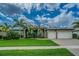 Beautiful single-story home featuring a well-manicured lawn, mature palm trees, and a spacious three-car garage at 3815 Gaviota Dr, Sun City Center, FL 33573