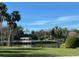 Scenic lake view showcasing a covered dock against a backdrop of trees and a clear blue sky at 5980 Central Ave, New Port Richey, FL 34653