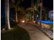 Evening view showcasing a backyard fire pit, tropical plants, and pool with stylish outdoor lighting at 751 34Th Ne Ave, St Petersburg, FL 33704