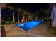 Backyard view of a sparkling pool, spa, fire pit, and tropical landscaping illuminated at night at 751 34Th Ne Ave, St Petersburg, FL 33704