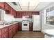 Traditional kitchen with wood cabinets, double sink, white appliances, and white backsplash at 831 Maple Ct # 303, Dunedin, FL 34698