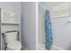 Cozy bathroom featuring a toilet, cabinet, shower with a blue shower curtain and neutral tile floor at 3611 19Th N St, St Petersburg, FL 33713