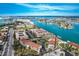 Aerial view showcases waterfront condos near waterway, lush greenery, tennis courts, and convenient parking at 8711 Blind Pass Rd # 307A, St Pete Beach, FL 33706
