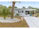 Inviting single-story home with a carport, manicured yard with rocks, and a towering palm tree at 14912 Brookridge Blvd, Brooksville, FL 34613