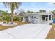 Charming single-story home with a pristine white exterior, spacious carport and manicured landscaping with palm trees at 14912 Brookridge Blvd, Brooksville, FL 34613