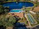 Aerial view showcasing community pool, shuffleboard courts, clubhouse, parking, and scenic lake, ideal for recreation at 1725 Pine Ridge E Way # E, Palm Harbor, FL 34684