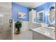 Stylish bathroom with blue accent wall, double vanity, and glass-enclosed shower with tiled walls at 18732 Wimbledon Cir, Lutz, FL 33558