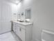 Bathroom featuring marble-style tile, toilet, double vanity, lighted mirrors, and a neutral color palette at 644 3Rd S Ave # 302, St Petersburg, FL 33701