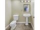 Small bathroom with a pedestal sink and toilet and neutral-colored walls at 1350 Gulf Blvd, Clearwater, FL 33767