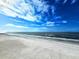 Wide sandy beach meets the ocean under a sky with bright, streaky clouds at 18650 Gulf Blvd # 413, Indian Shores, FL 33785
