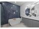 Modern bathroom featuring a freestanding tub, navy blue tile wall, and double sink vanity with unique mirrors at 1905 W Erna Dr, Tampa, FL 33603