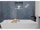 Close up of modern bathroom with a soaking tub and a navy blue tiled accent wall at 1905 W Erna Dr, Tampa, FL 33603