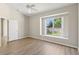 Spacious bedroom featuring wood floors, a ceiling fan, and a large window overlooking the backyard at 31447 Shaker Cir, Wesley Chapel, FL 33543