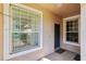 Exterior shot of front entrance with storm door, tan siding, and brick floor at 31447 Shaker Cir, Wesley Chapel, FL 33543