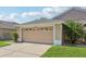 A light brown two-car garage attached to the residence with green grass and a palm tree at 31447 Shaker Cir, Wesley Chapel, FL 33543