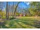 Large backyard with a red storage shed surrounded by tall trees, offering both functionality and serene landscape at 11201 Knotty Pine Dr, New Port Richey, FL 34654