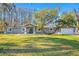 A charming single-story home is surrounded by a lush green lawn and mature trees at 11201 Knotty Pine Dr, New Port Richey, FL 34654