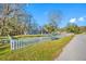 A view of the home from the street shows a grassy yard and a white picket fence at 11201 Knotty Pine Dr, New Port Richey, FL 34654