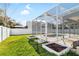 Backyard featuring a screened-in pool, garden plots, and a well-maintained lawn at 1600 Gray Bark Dr, Oldsmar, FL 34677