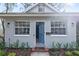 Inviting front entrance with a vibrant blue door, flanked by symmetrical windows and lush landscaping at 3616 W Morrison Ave, Tampa, FL 33629