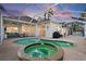 Wide shot of an outdoor pool and patio area with a hot tub and screened-in enclosure at dusk at 4531 Swordfish Dr, Bradenton, FL 34208