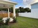 Covered patio and backyard with green lawn and white fence at 11594 Oak Ln, Largo, FL 33778