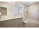 Bathroom featuring a dual-sink vanity, bathtub with tiled surround, and a bright window at 11594 Oak Ln, Largo, FL 33778