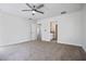 Spacious bedroom featuring neutral carpet, a ceiling fan, and doors leading to a bathroom at 11594 Oak Ln, Largo, FL 33778