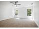 Spacious bedroom with neutral carpet, two windows, and a modern ceiling fan at 11594 Oak Ln, Largo, FL 33778