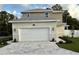 Two-story home featuring a gray roof, attached garage, and gray paver driveway at 11594 Oak Ln, Largo, FL 33778
