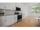 Modern kitchen with stainless appliances, white cabinets, backsplash, and wood-look flooring at 11594 Oak Ln, Largo, FL 33778