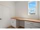Well-lit laundry area with a wooden countertop, white cabinetry, and a bright window, creating a pleasant and efficient workspace at 11594 Oak Ln, Largo, FL 33778