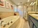 Well-lit bathroom featuring a jacuzzi tub with tile surround and a glass enclosed shower with granite countertops at 3909 W Eden Roc Cir, Tampa, FL 33634