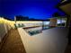 Inviting backyard pool illuminated by string lights, surrounded by a brick and painted concrete patio at 3909 W Eden Roc Cir, Tampa, FL 33634