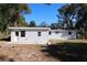 Back exterior view with neutral colored walls, several windows, and dirt yard at 7160 Lenape Cir, New Port Richey, FL 34653