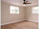 Spacious bedroom featuring wood-look flooring, two windows, and neutral wall colors at 7160 Lenape Cir, New Port Richey, FL 34653