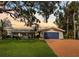 Charming single-story home features a well-manicured lawn, lovely landscaping and a bright blue garage door at 1985 Byram Dr, Clearwater, FL 33755