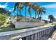The backyard has stone retaining wall, white fence, palm trees and privacy hedge at 5606 Seagrass Pl, Apollo Beach, FL 33572