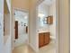 Hallway view leading to a bathroom showcasing a vanity with a wood cabinet and artwork above the toilet at 5606 Seagrass Pl, Apollo Beach, FL 33572