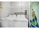 A practical laundry room with washer, dryer, and storage shelves, enhanced by a mermaid-themed mural at 100 Bluff View Dr # 205C, Belleair Bluffs, FL 33770