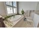 Soaking tub with tile surround, next to a large window with white shutters, and a plant at 1308 Alhambra Dr, Apollo Beach, FL 33572