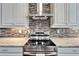 Close-up of updated stainless steel stove top and range hood against a tiled backsplash and granite counter at 1308 Alhambra Dr, Apollo Beach, FL 33572